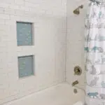 Remodeled bathroom shower with a white subway tile surround and two recessed glass mosaic niches in Salmon Creek, WA