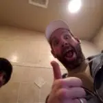 TLC Home Solutions remodeling contractors giving a thumbs-up inside a tiled bathroom during a home renovation