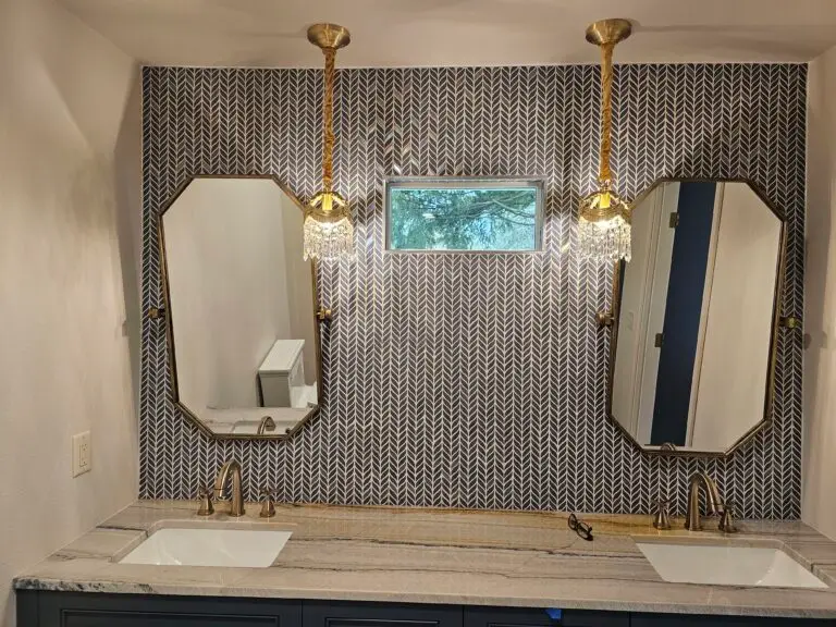 Bathroom mirrors with sconce lighting over a mosaic tile wall