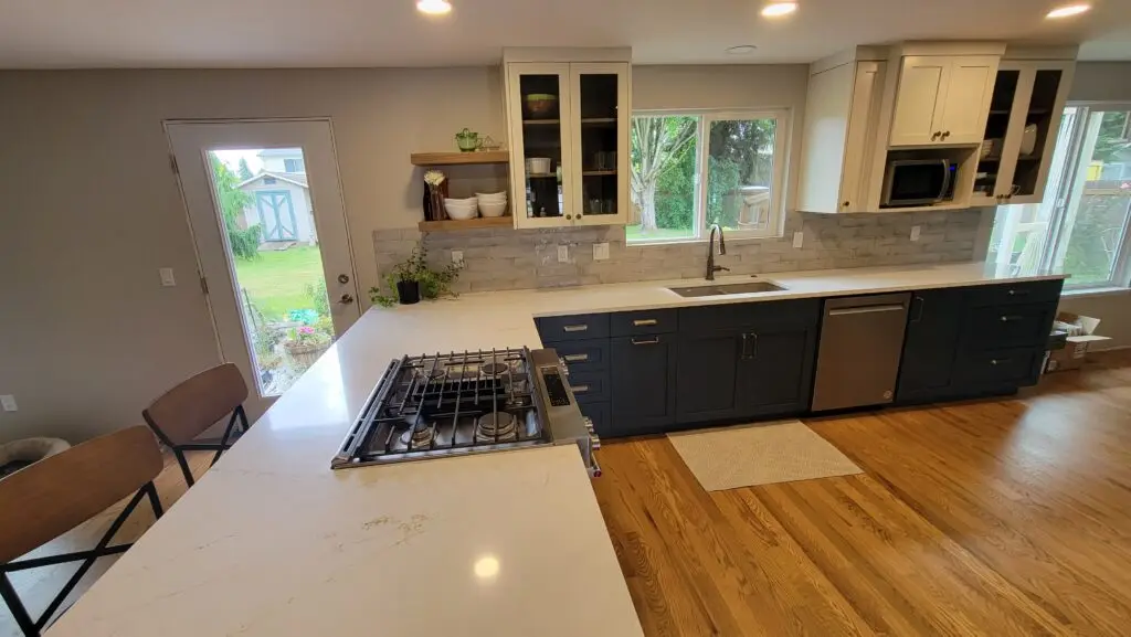 Remodeled kitchen with navy base cabinets, white upper cabinets, quartz countertops and a tile backsplash in Vancouver, WA