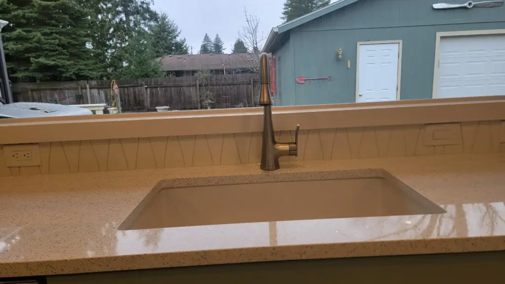 New quartz countertop with an undermount sink and bronze faucet beneath a kitchen window in Vancouver, WA