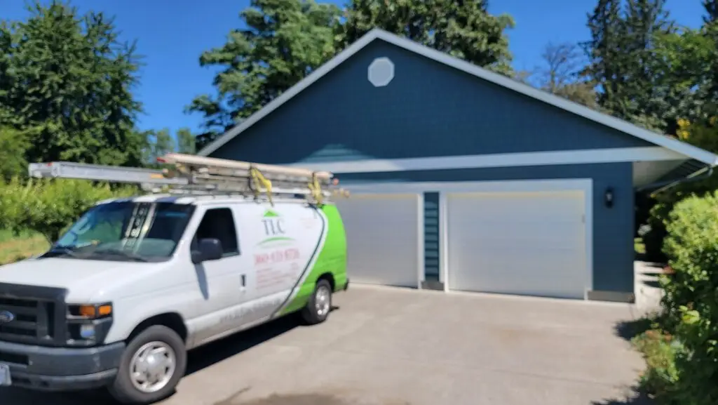TLC Home Solutions branded van parked at a detached garage finished in new teal siding and trim