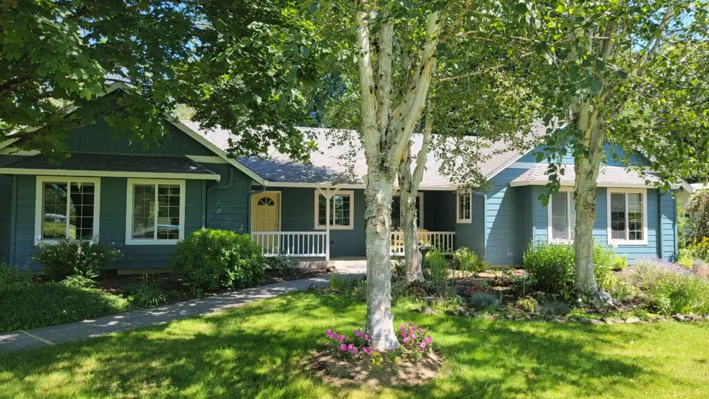 Single story home with new teal green siding, cream trim and a refreshed front porch after exterior work