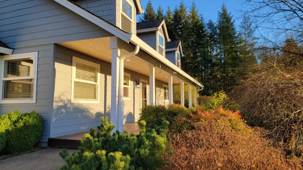 Blue lap siding home with a covered front porch and white columns after exterior work by TLC Home Solutions